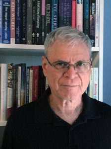Image of a man smiling, in front of a bookcase.