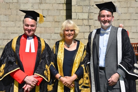 Two men and one woman in graduation ceremony robes