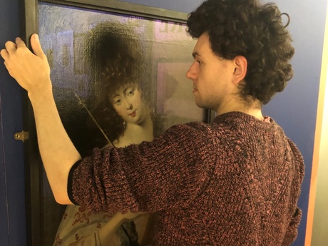 One of the team behind the exhibition hanging a painting of a woman