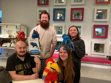 Zoology students with animal puppets and museum backdrop