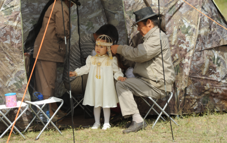 A relative helps a little girl with her Sakha national costume. Photo courtesy of Maksim Unarov