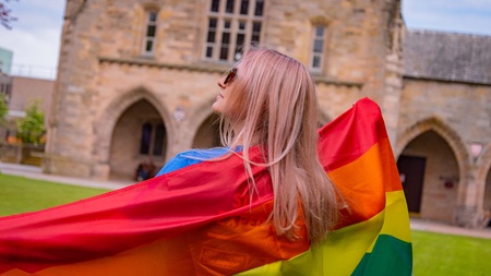 Person wearing LGBTQ+ flag on Elphinstone Lawn