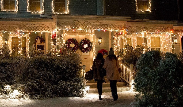 A scene from Gilmore Girls showing two characters walking up to a festively decorated house