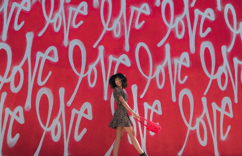Woman in front of wall with the words Love painted on it