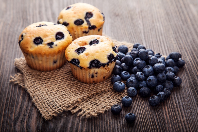 Blueberry muffins next to a pile of blueberries