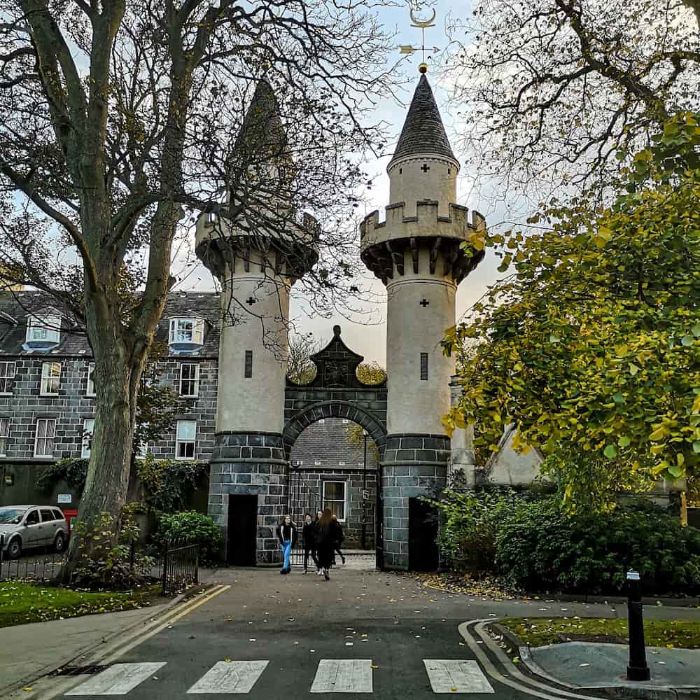 Students walk through Powis Gates on an Autumn day.