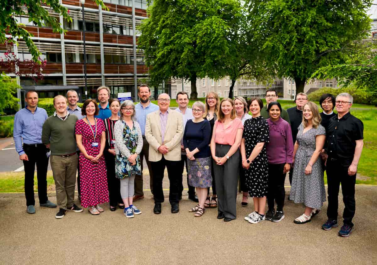 A group of around 20 people standing outside a modern uni building