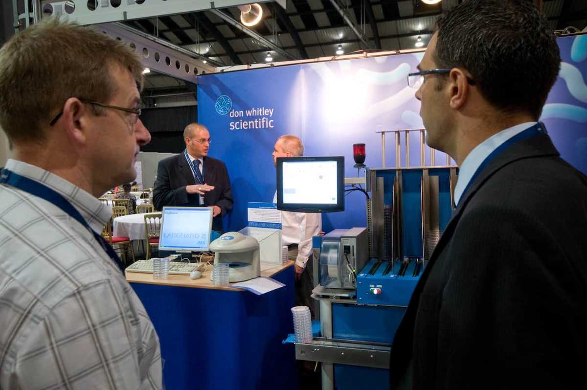 people talking in front of machine at event