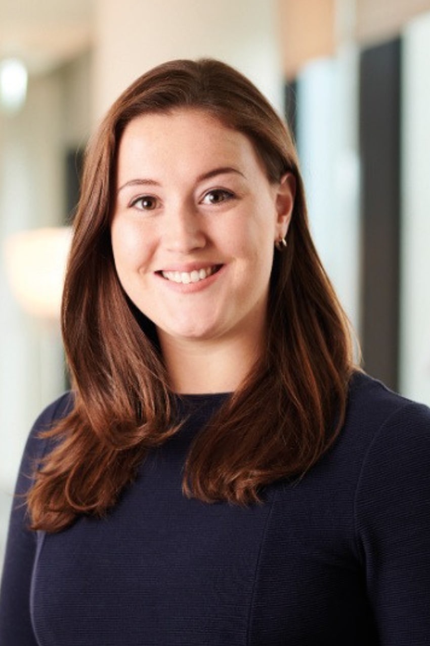 A brunette woman in a dark jumper smiling