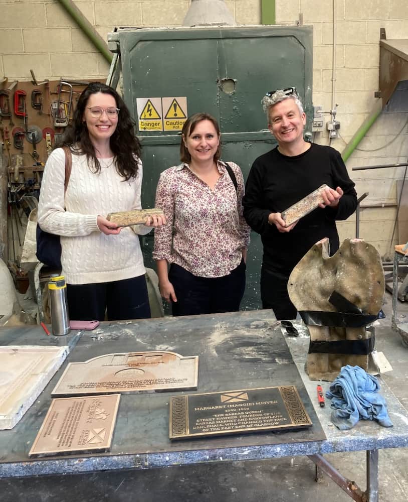 3 women in front of collection of old signs