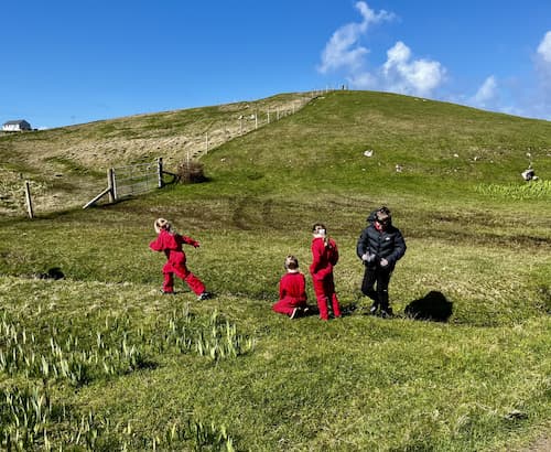 Children running around on a grassy hill