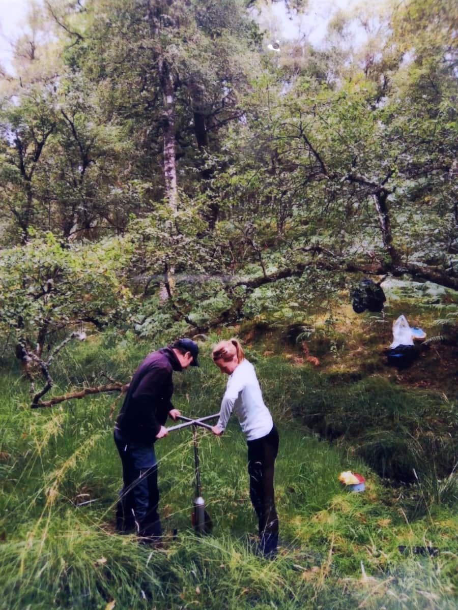 2 people boring hole in countryside