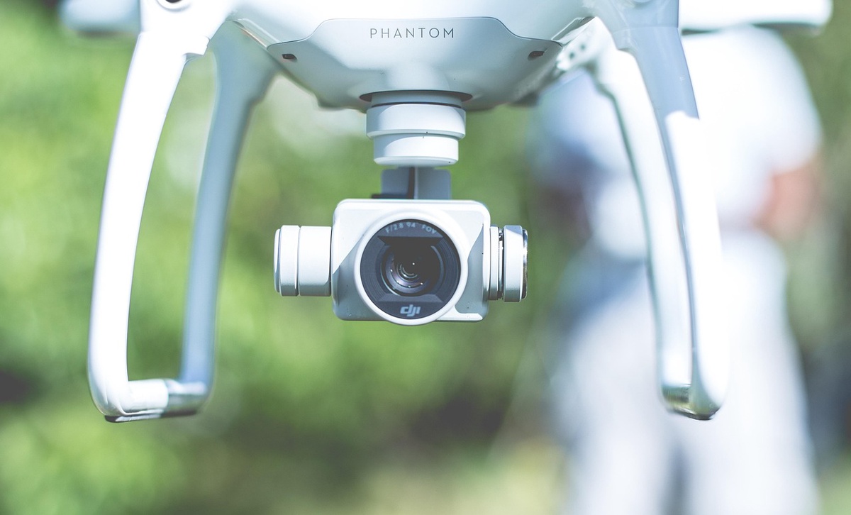 A close up of a camera attached to a drone hovering in mid-air