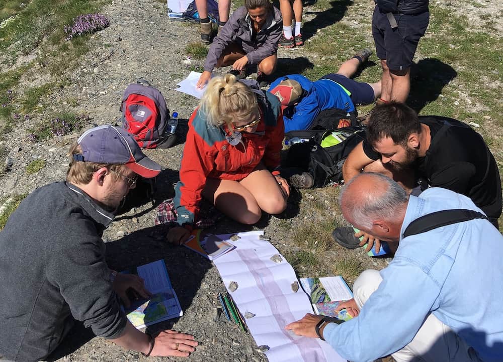 researchers sitting on ground looking at papers