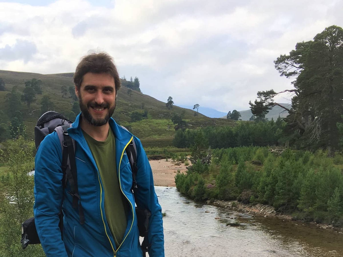 bearded man standing by river by forest