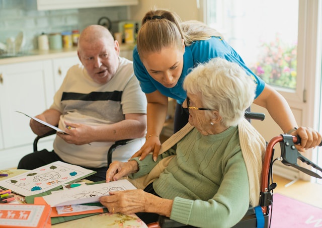 nurse helping an elderly woman and man