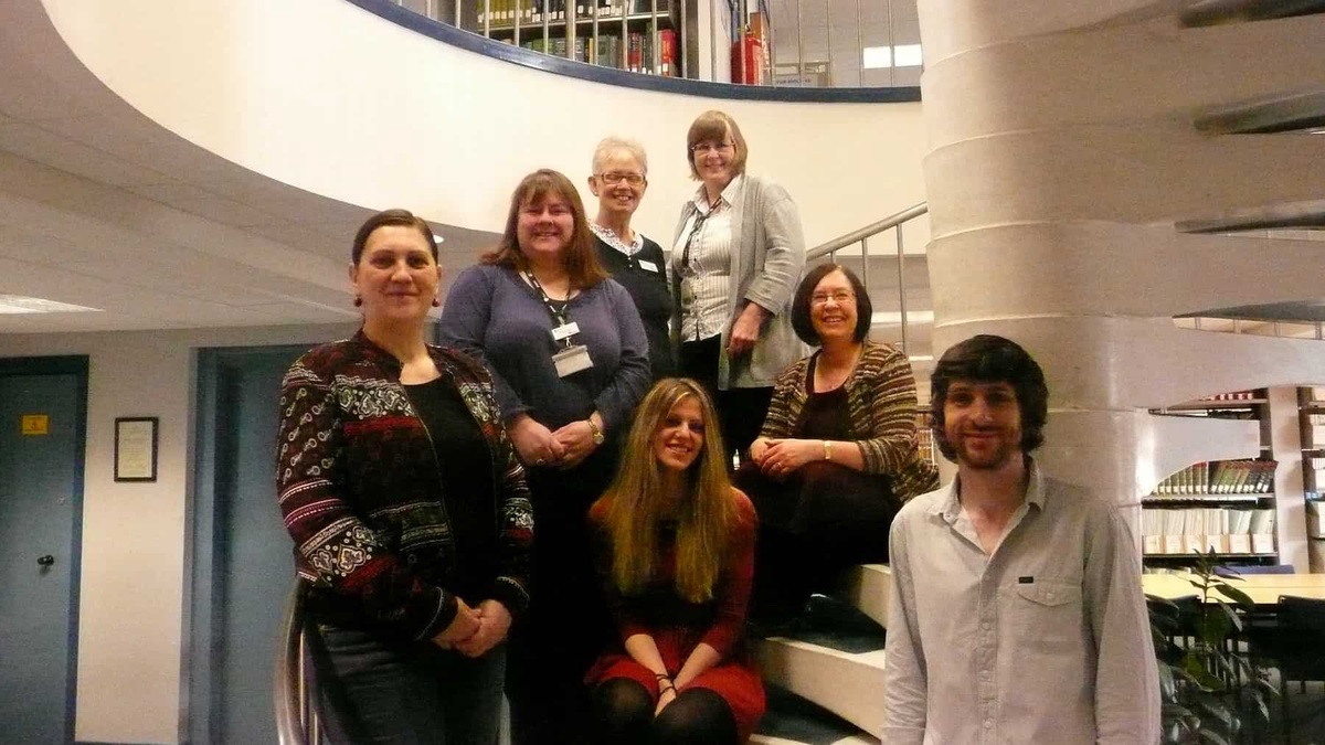 7 library staff stood on a spiral staircase