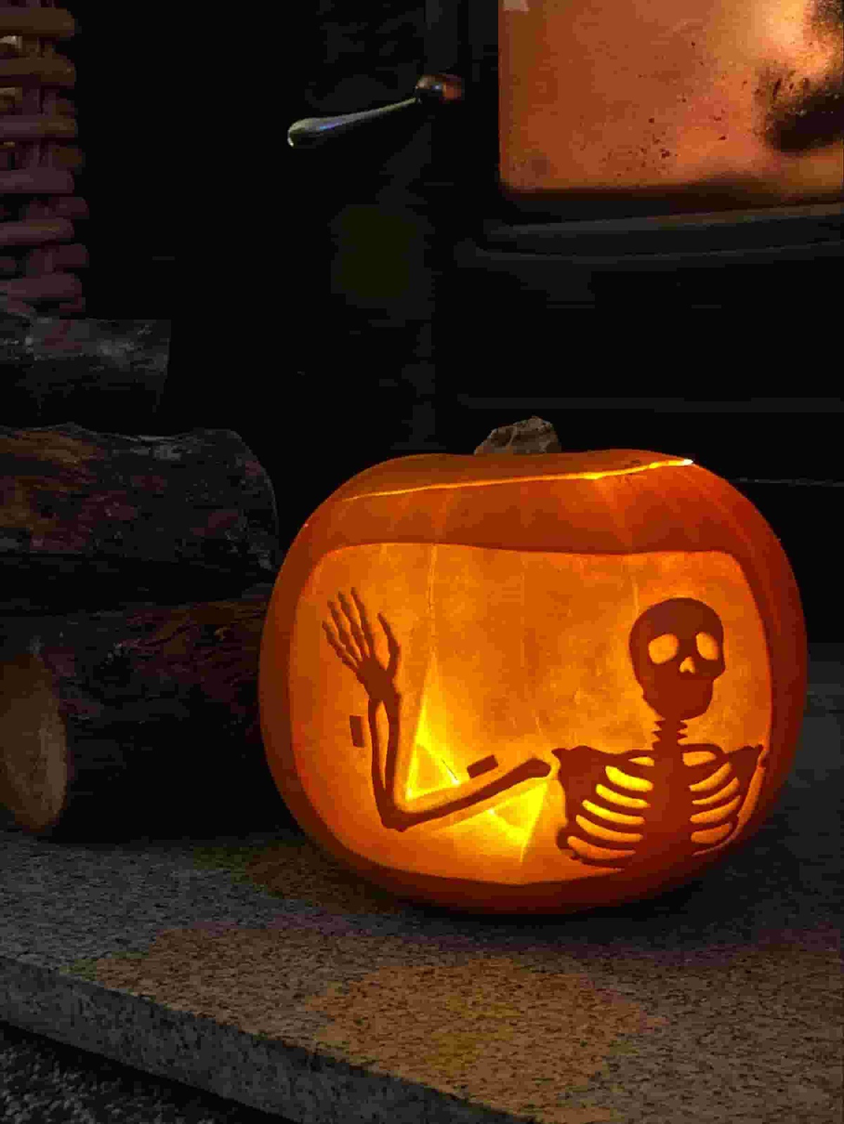 A large pumpkin, it has been carved so that you see a human skeleton from the waist up, on it’s upper and lower arm bone you can see some sort of metal implant