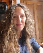 Dr Syrithe Pugh, sitting in front of wooden panelling in a sunlit room.