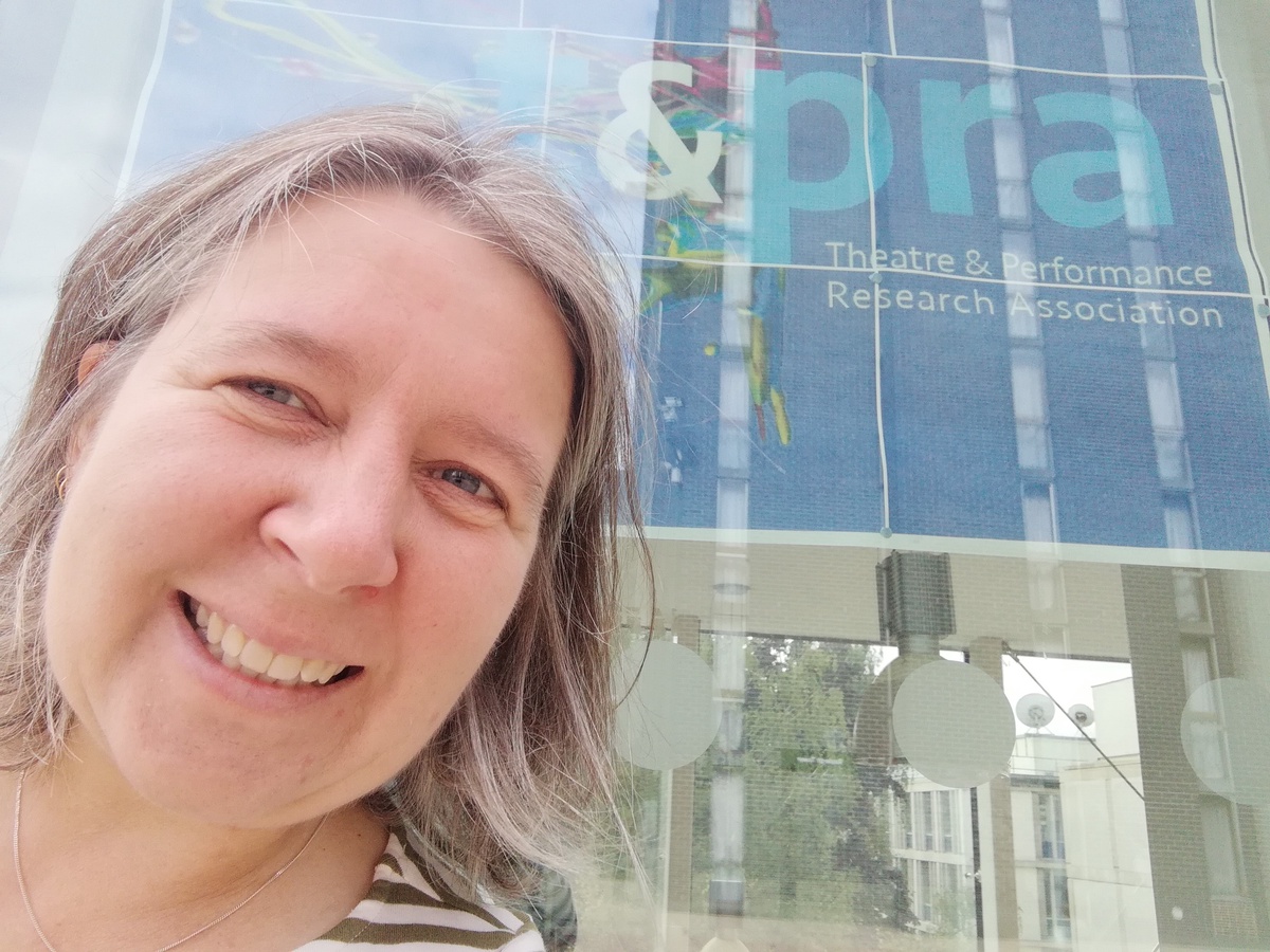 A student standing outside a building. They are smiling.