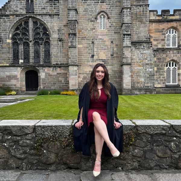 Iliana Hernandez Valdivia sitting on stone wall in front of King's College chapel