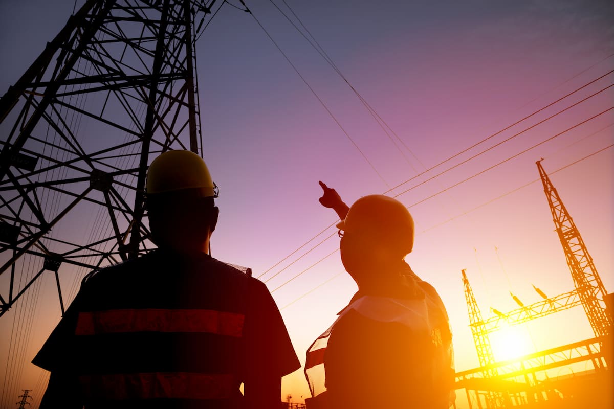 Two engineers at sunset pointing at a pylon