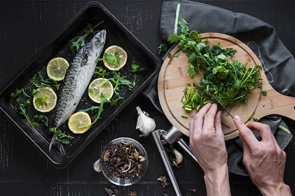 Hands cutting parsley to garnish fish