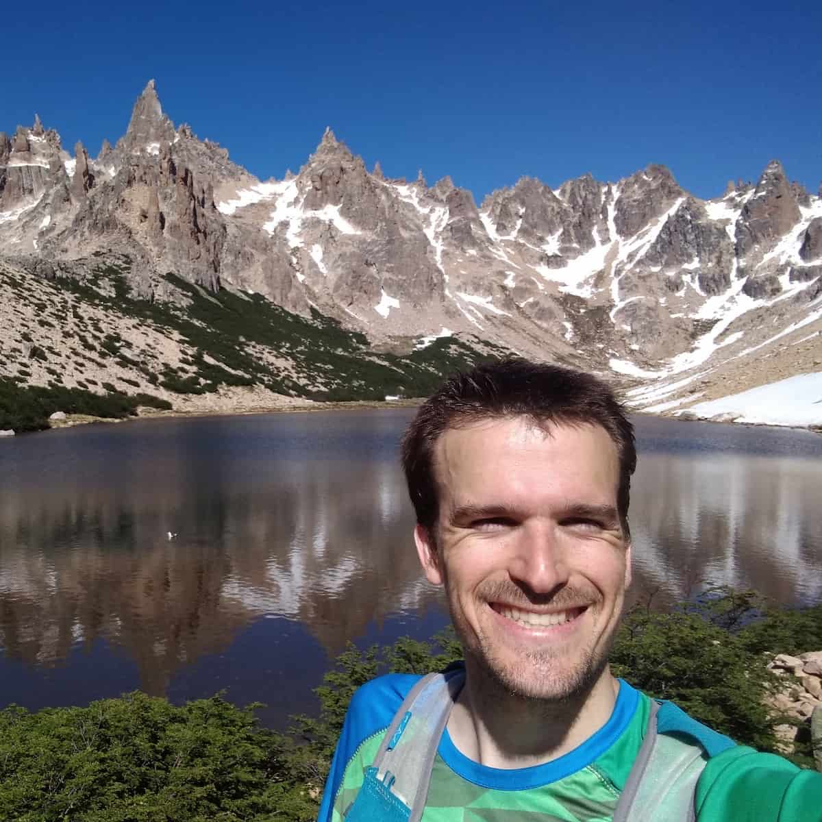 smiling man in front of mountain lake