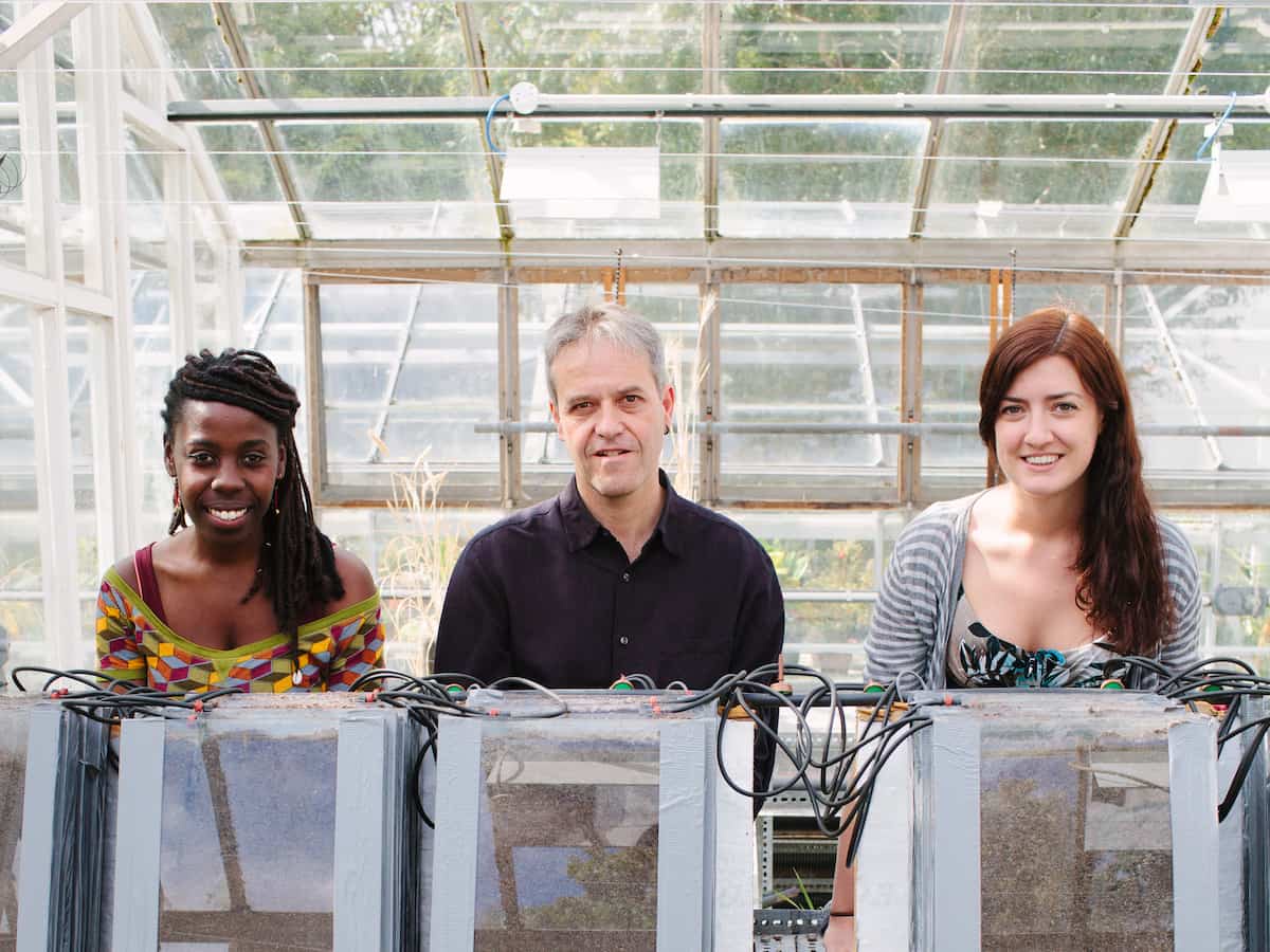 3 smiling people standing in front of equipment