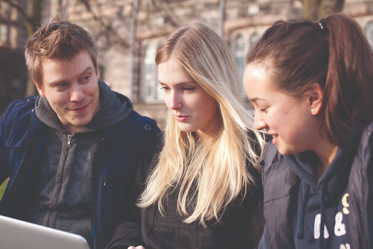 three students working on a laptop
