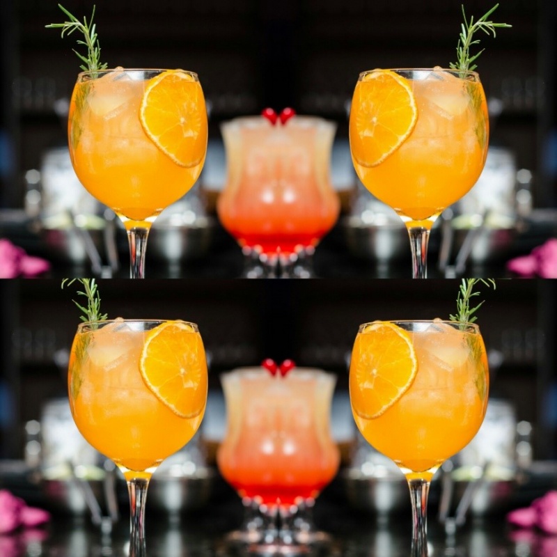 Orange cocktail in a glass with a sprig of rosemary garnish