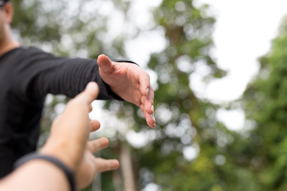 Hands reaching towards each other with trees in the background