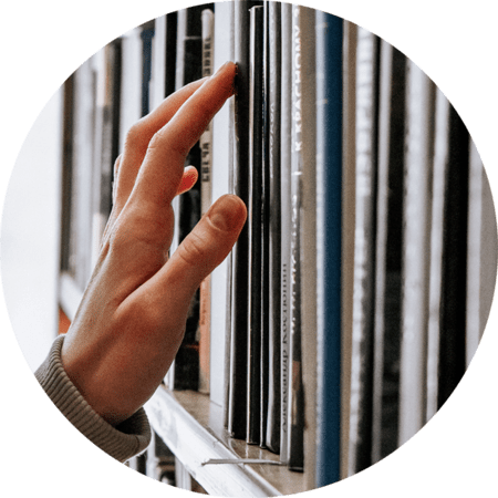 a hand reaching for a book on a shelf