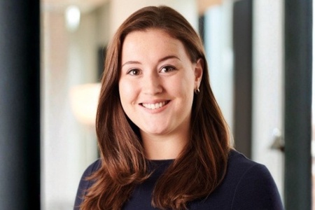 A brunette woman in a dark jumper smiling
