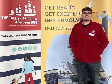 Young man standing in front of tall ships banners