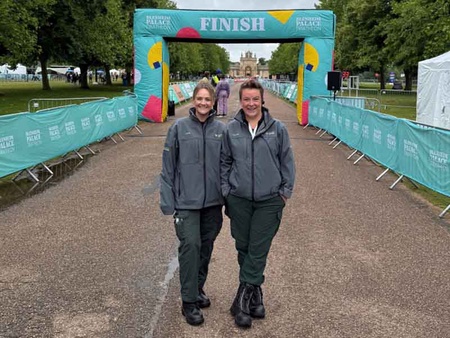 Two young women stand near the finish line of a marathon