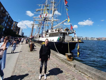 Female student in front of a tall ship