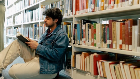 Student sitting in the library reading a book