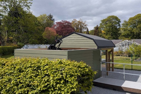 Anne H Cruickshank Observatory viewed from the southeast. The observatory roof is opened away from the camera, with greenhouses behind. The John Cruickshank Telescope is visible in the foreground. Credit: Charles Wang