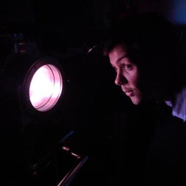 Scott Doyle looking into a chamber containing a purple plasma