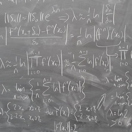 A blackboard with chalk calculations showing the derivation of the Lyapunov exponent for a map