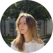 Woman with brown hair standing outside with tree in background