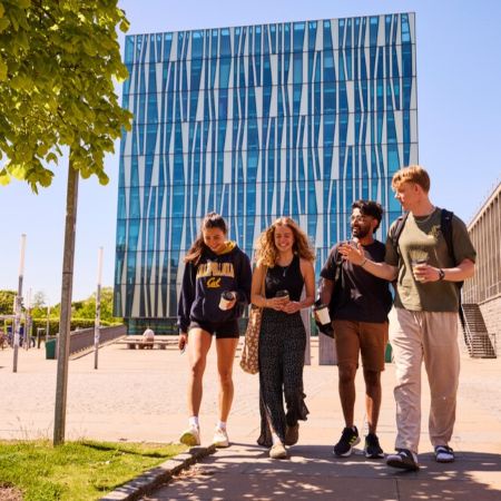Four students walking in front of a library building