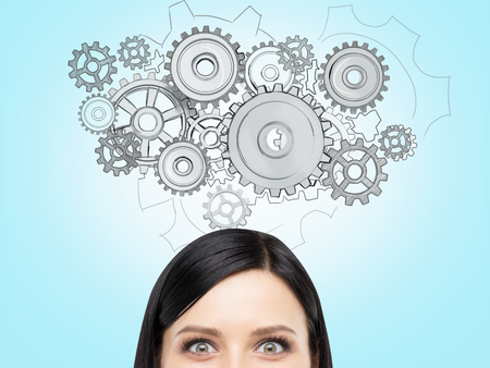 top of womans head showinh alert eyes with cogs above her head on light blue background