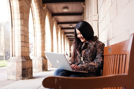 Students sitting on a bench with laptop
