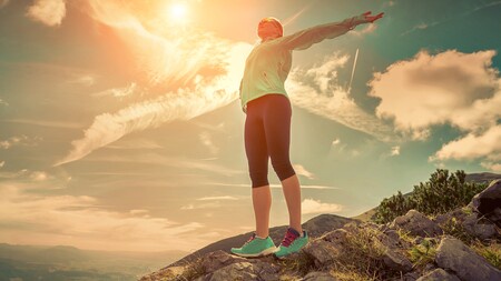 A human stands in sports gear atop a hill or mountain