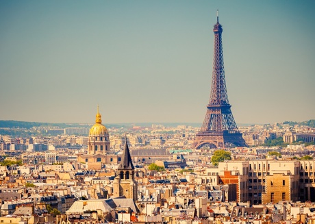 a city skyline and a sunny sky, with lots of old and modern buildings, church domes and steeples and the Eiffel Tower.