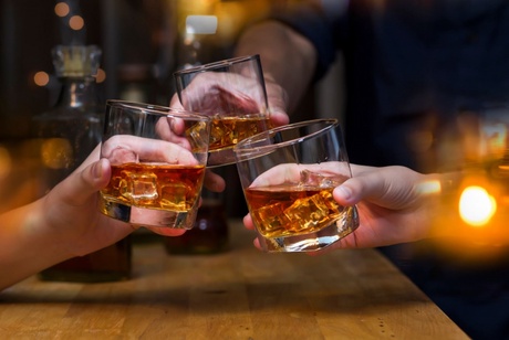 Three whisky glasses raised in a 'cheers' motion