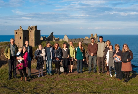 People posing in front of seaside castle ruins