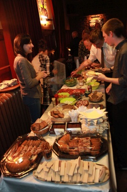 A table of food surrounded by attendees.